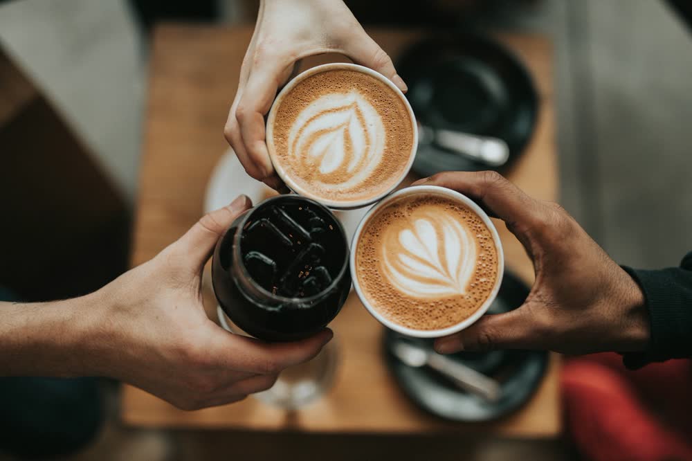 Two lattes with heart latte art next to potted plants