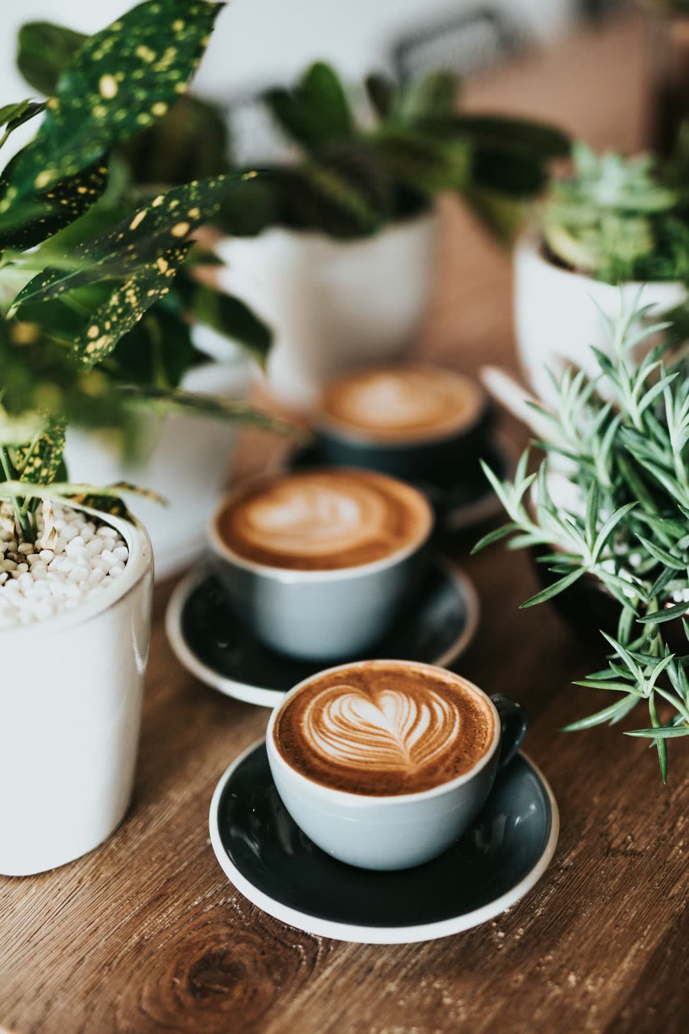 Friends clinking latte cups over a wooden table